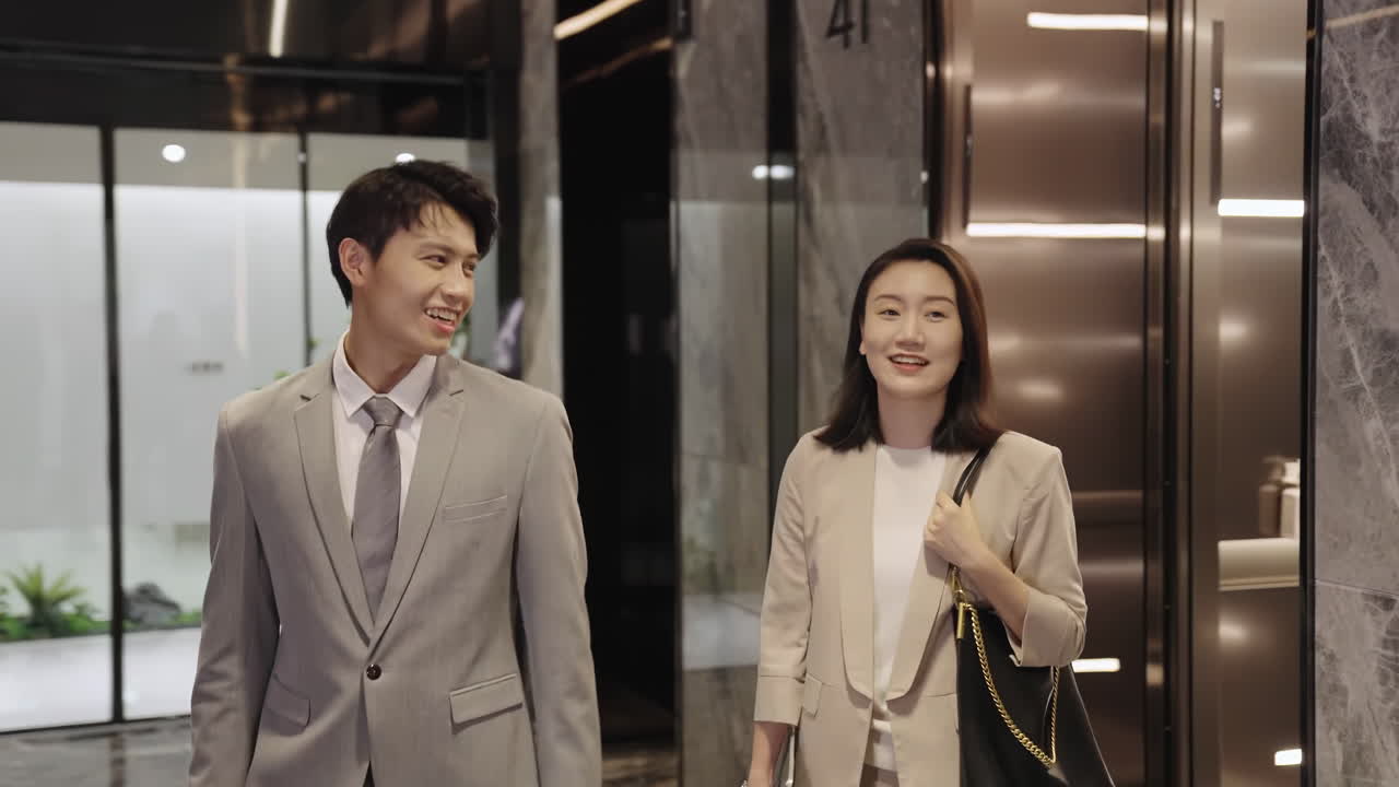 Hai đồng nghiệp công ty vui vẻ, tích cực trò chuyện, nói chuyện, tận hưởng cuộc trò chuyện, thảo luận công việc khi bước ra khỏi thang máy. Các nhân viên chuyên nghiệp rời thang máy để rời cuộc họp, cuộc hẹn.