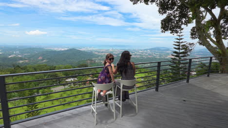 mom and daughter sit on the veranda of the hillside cafe in kokol hill near kota kinabalu, sabah, malaysia. pov shot