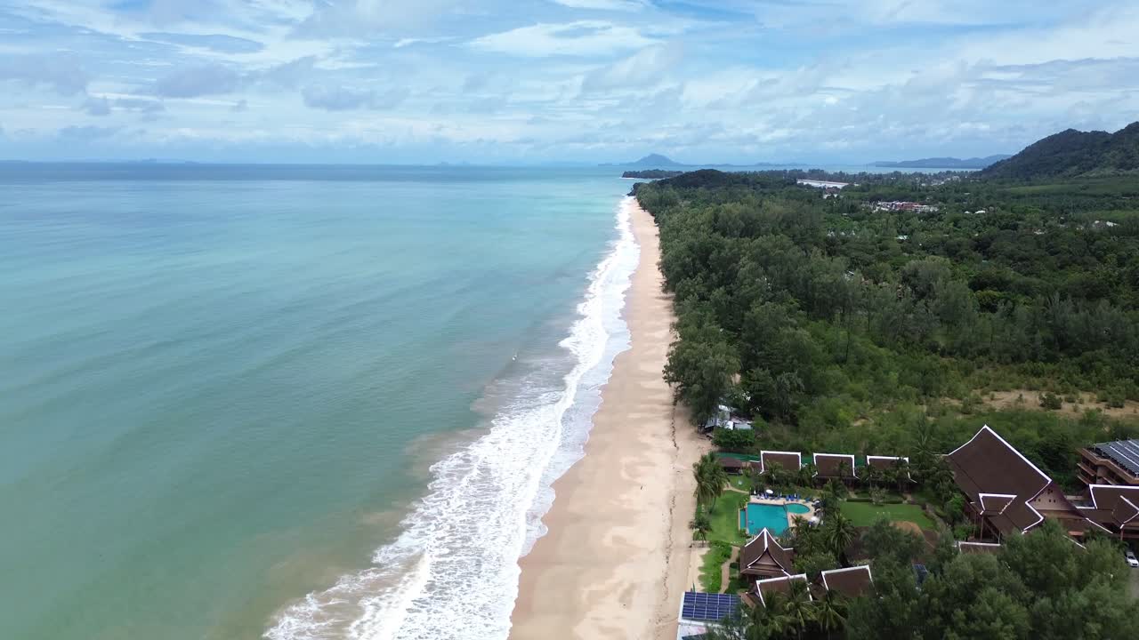 Vídeo aéreo de bungalows costeros junto a la costa de Koh Lanta, Tailandia, rodeados de palmeras y paisajes tropicales isleños con mar turquesa
