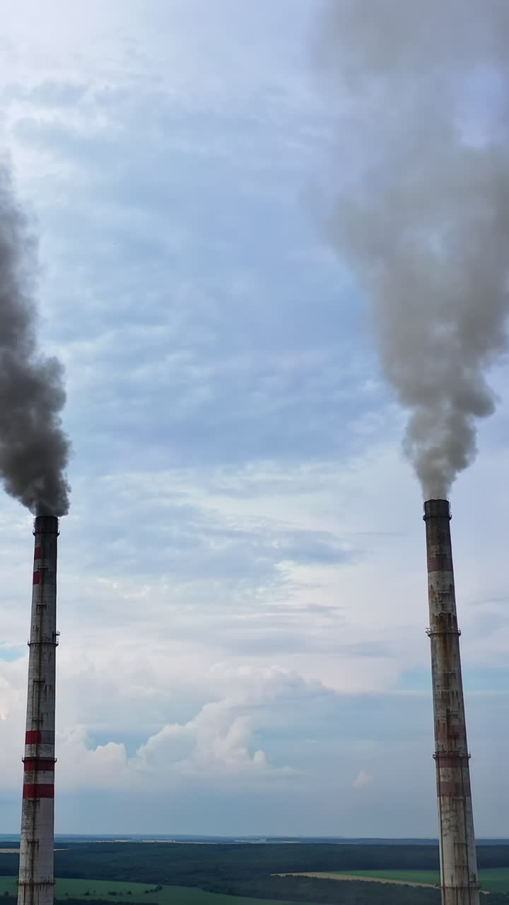 Industrial factory pipes emission gas and smoke. Chimneys with harmful fumes on sky background. Concept of ecology crisis and atmosphere pollution. Vertical video