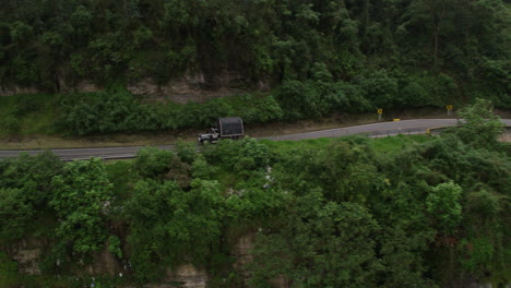 pequeña camioneta graciosa conduce una pintoresca carretera de montaña empinada solitaria a gran altitud como avión no tripulado aéreo sigue el vehículo con el movimiento 3d panorámico de este viaje por carretera