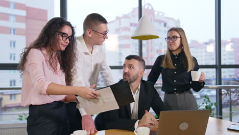 long-haired brunet woman holding documents in her hands showing them to colleagues. office team approve what they hear and nod heads.