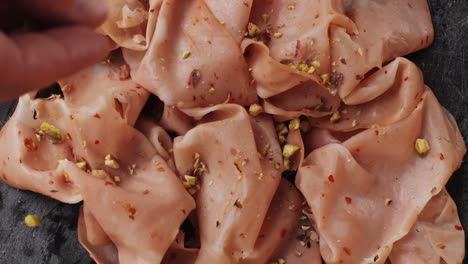 ham italian mordatella, man slices of traditional italian antipasti mortadella sausage on a wooden cutting board, close up macro of chicken or turkey jamon, fat breakfast dish.