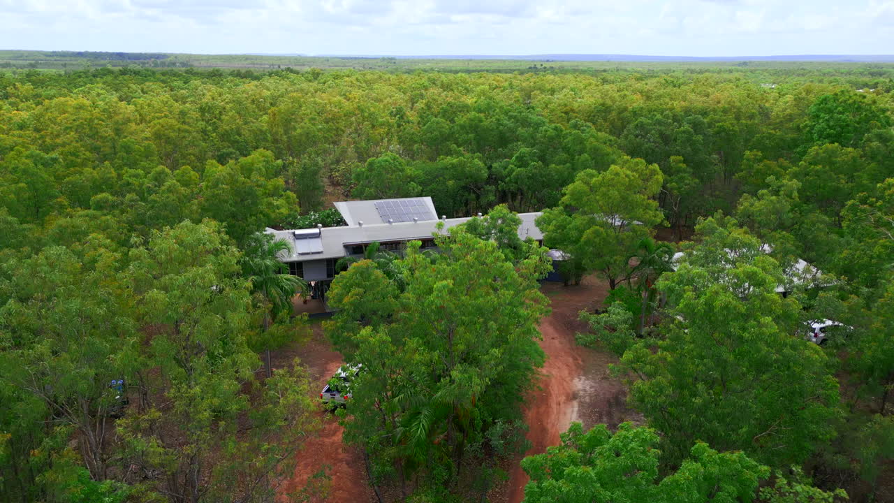 Vehicle driving down dirt road towards rural house