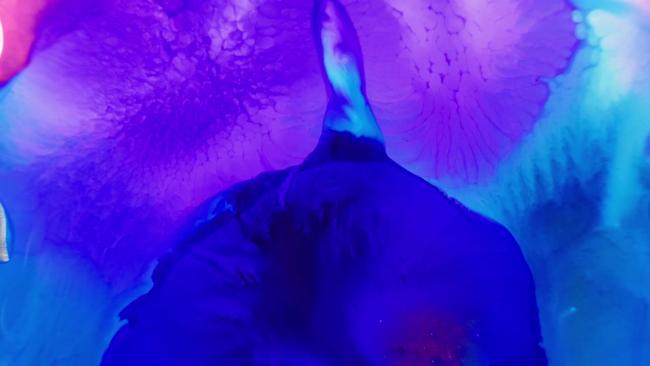 Inchiostro blu vivido e viola che si diffonde nell'acqua con un picco centrale scuro
