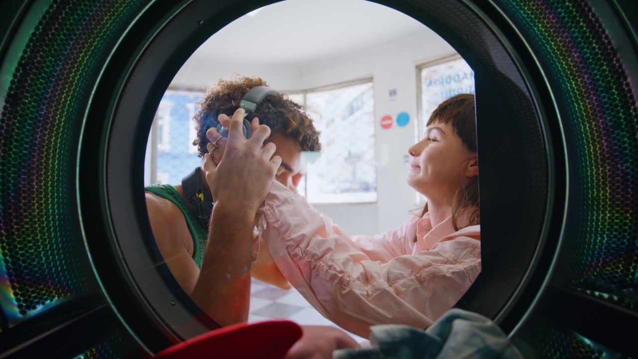 Teenage friends listening music in laundry room closeup. Smiling couple washing