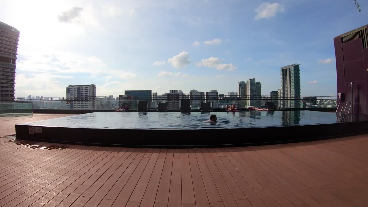 Timelapse of a person swimming in a hotel rooftop pool, Singapore, UHD