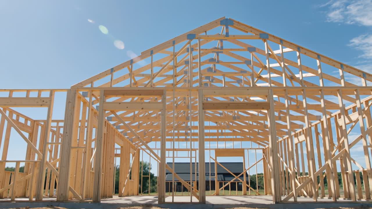 Wooden frame structure of a new residential house under construction against a clear blue sky