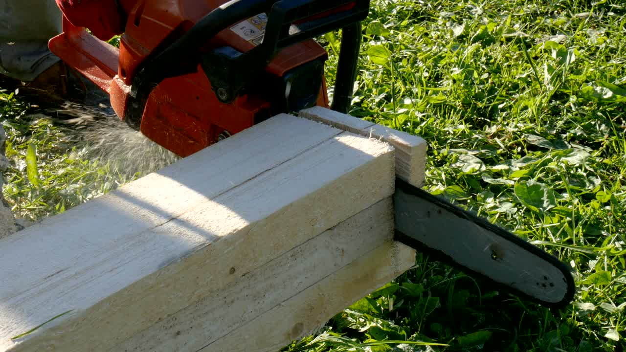 el trabajador corta las tablas de madera con una sierra de gasolina.