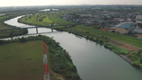 Puente-Ferroviario-Sobre-Las-Tranquilas-Aguas-Del-Río-Arakawa-Con-Vistas-A-La-Ciudad-De-Fujimi-En-El-Lado-Derecho-En-Saitama,-Japón