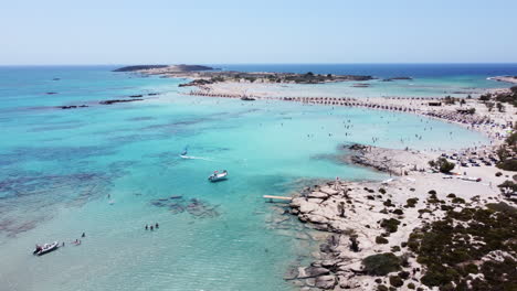 Aerial-flying-backwards-over-beautiful-Elafonissi-beach,-tourist-enjoying-sunny-day