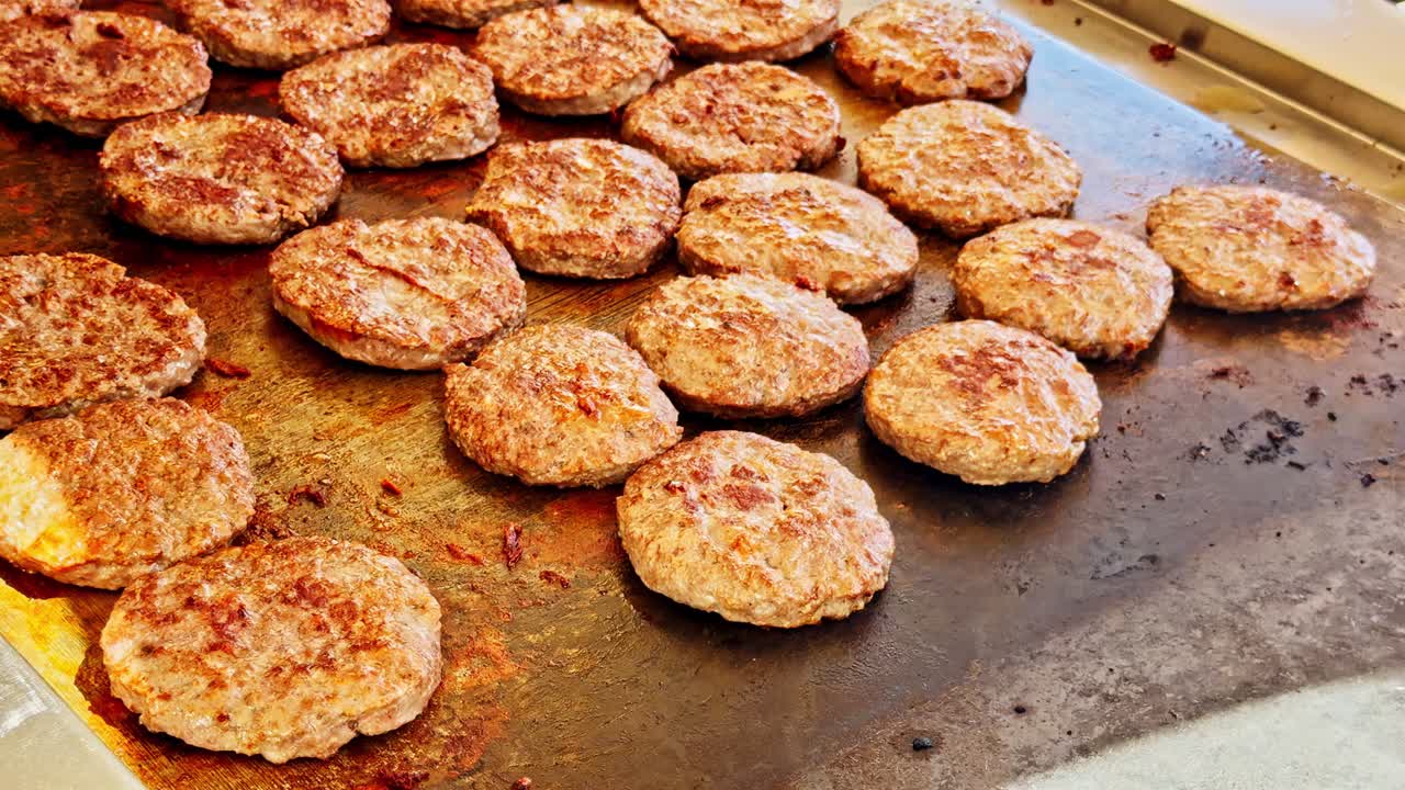 Meat patties cooking on flat grill at restaurant kitchen, Egyptian culinary preparation