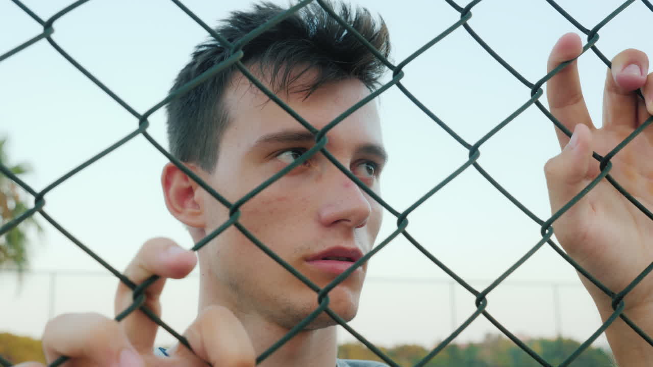 retrato de un adolescente triste mirando a través de la cuadrícula