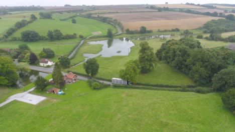 aerial video rotating to capture an agricultural truck as it arrives at a farm along a country road in a small countryside village in rural yorkshire, uk