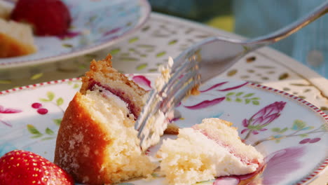 close up of woman eating slice of strawberry sponge cake