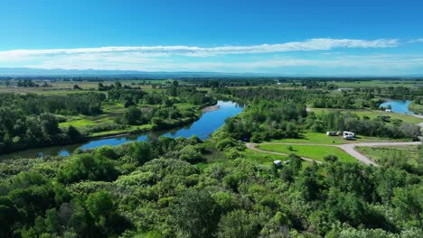 lush vegetation surrounding calm river in saint anthony, idaho - aerial drone shot