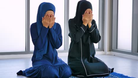 전통적인 히자브를 입은 두 명의 아시아 무슬림 젊은 여성들이 모스크에서 하나님을 찬양하고 이슬람 신앙을 실천하고 있습니다.