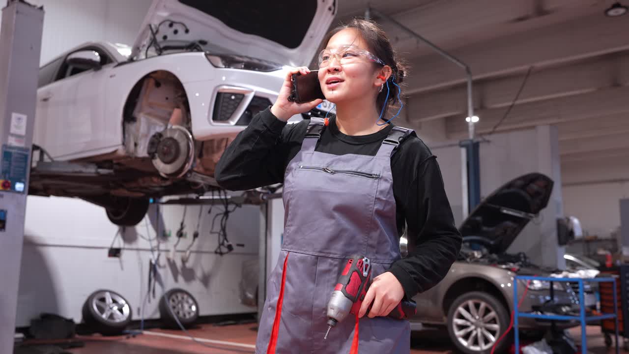 自動車修理工場で電話で話している女性整備士