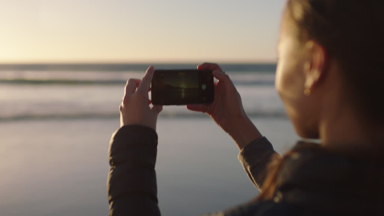 primer plano de una mujer joven tomando una foto de una hermosa puesta de sol en la playa usando tecnología de cámara de teléfono inteligente disfrutando de un estilo de vida tranquilo de vacaciones de verano