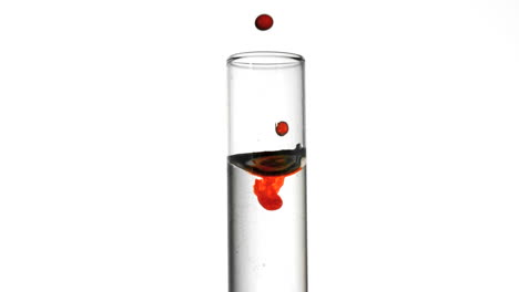 drop of blood falling into test tube of water close up