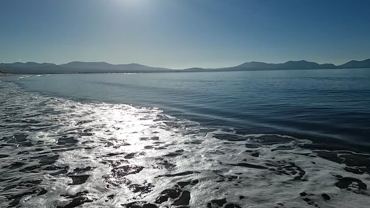 천천히 움직이는 조류 파도가 하늘의 안개  ⁇ 에 스프래싱 빛나는 해가 뜨는 스노우도니아 산맥 스카이라인