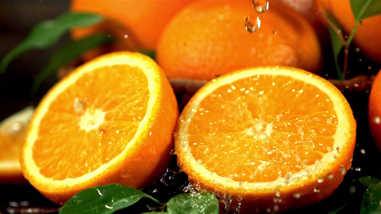 Acqua che schizza su mezze arance fresche al rallentatore.
