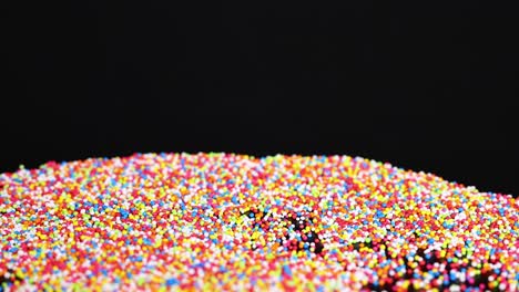 vibrant sprinkles cascade onto a black surface