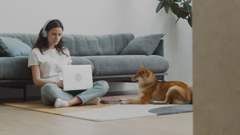 young woman working on her laptop at home next to her dog 1