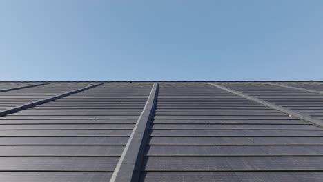 tejas solares instaladas en el techo de un edificio comercial bajo un cielo azul claro.