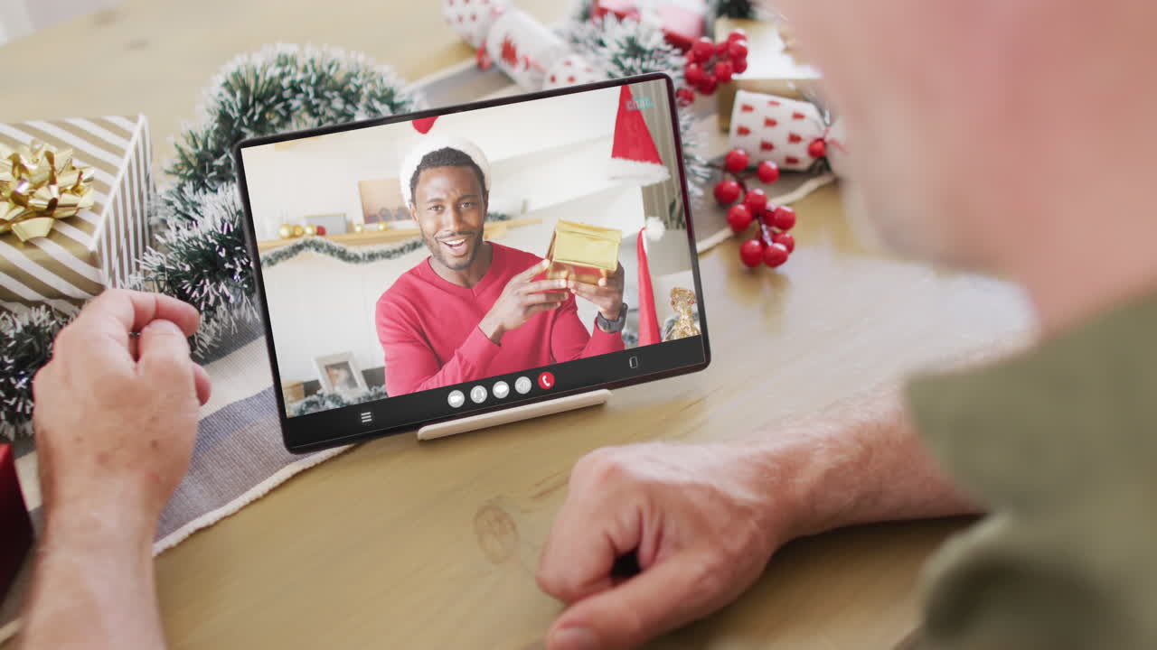 hombre caucásico con decoraciones de navidad teniendo llamada de video de tableta con hombre afroamericano