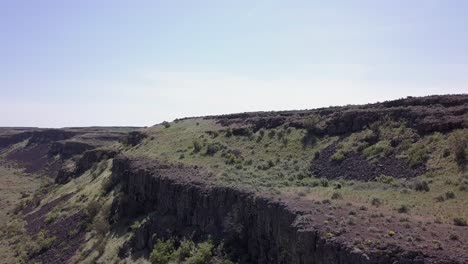 Aerial-rises-past-rock-cliffs-to-sagebrush-Scablands-on-plateau-above