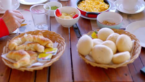 hotel table with breakfast served, homemade kneaded bread and freshly baked croissant are seen