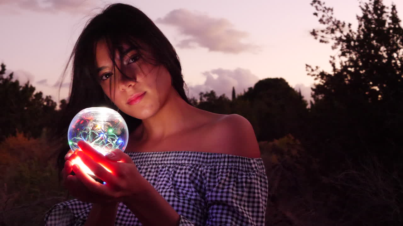 A beautiful woman wizard wandering in a fantasy landscape with a magic spiritual orb glowing in illuminated light