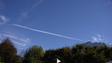 contrail with blue sky and alpine mountains near the town of annecy, wide locked shot