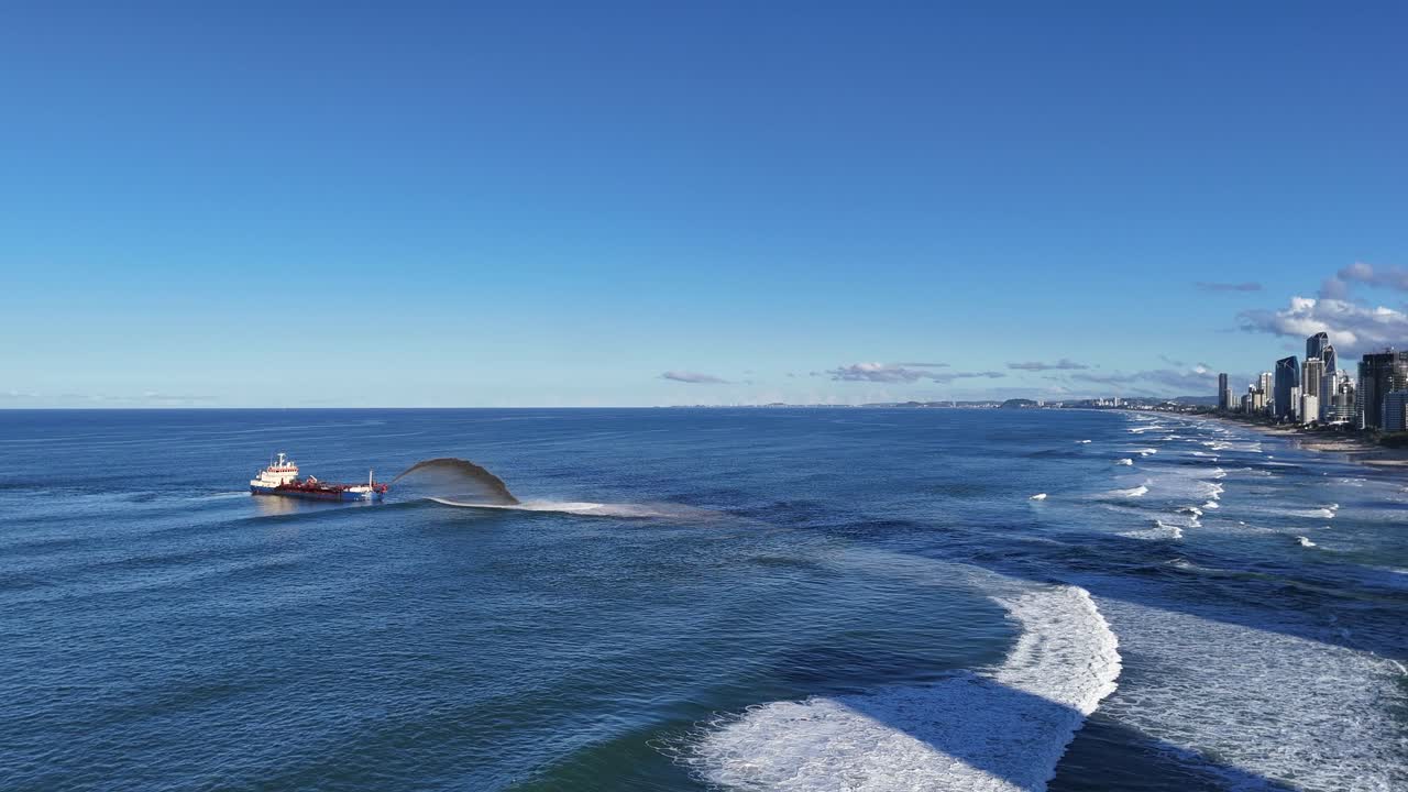 Aerial view of a dredger pumping sand in the Pacific Ocean near Gold Coast, Australia, under clear blue skies
