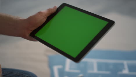 Unknown-man-showing-green-screen-to-camera.-Guy-using-tablet-for-design-indoors.