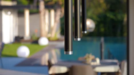 stylish kitchen illumination: close-up of three black kitchen fixtures with silver ends against outdoor pool and garden