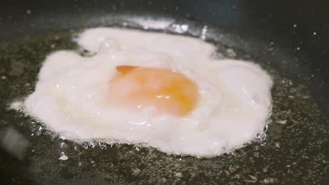 fried egg bubbling in hot oil being splashed in slow motion to cook yolk on top. cooking protein rich breakfast fresh healthy food