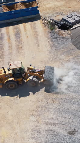 asphalt plant with running bulldozer. the plant serves the needs of road construction. industrial machine is loading rubbles. aerial view. vertical video