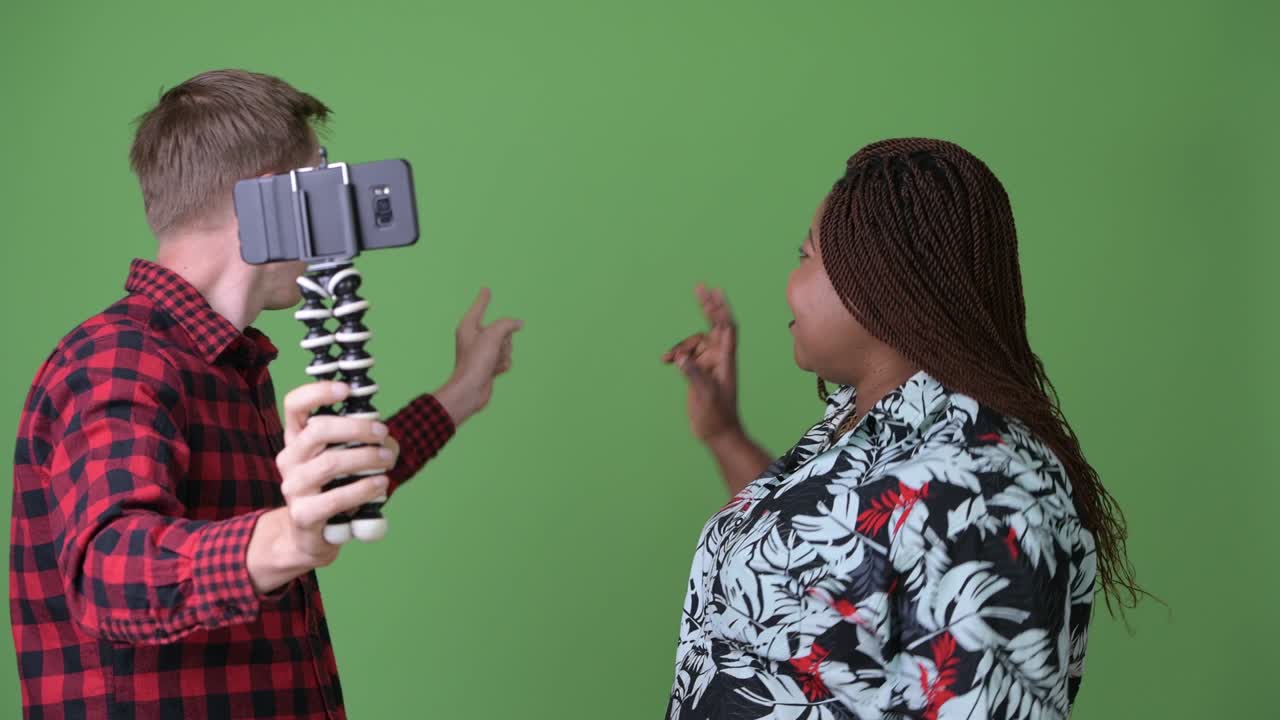 mujer africana con sobrepeso y un joven escandinavo juntos contra un fondo verde