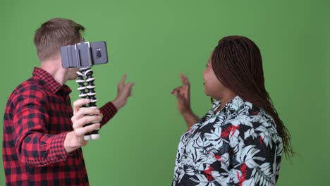 overweight african woman and young scandinavian man together against green background