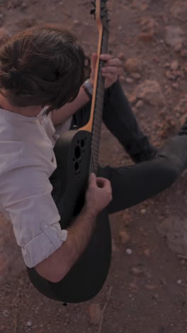 man playing an acoustic guitar outdoors