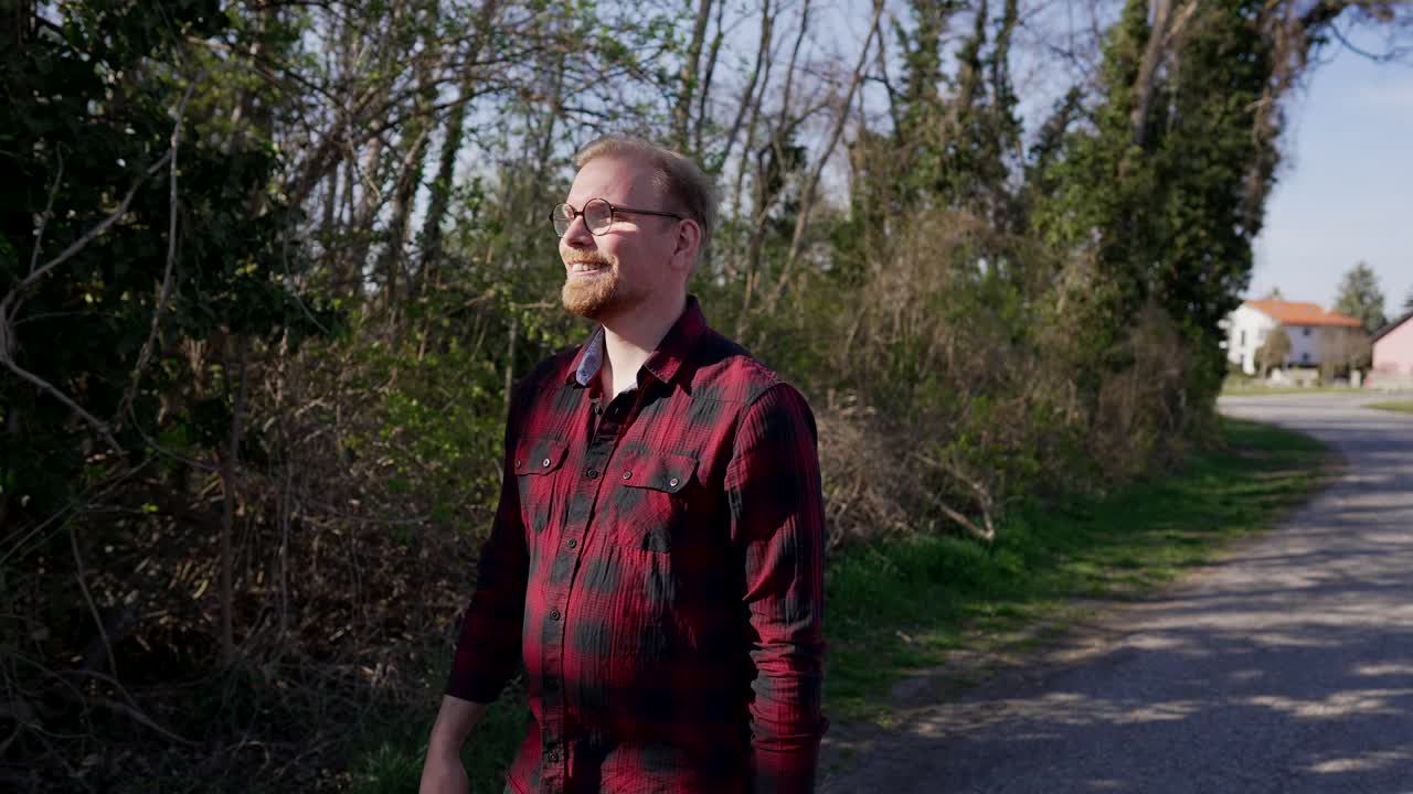 joven caucásico caminando por la calle, sonriendo, disfrutando de la vida, cerca del frente