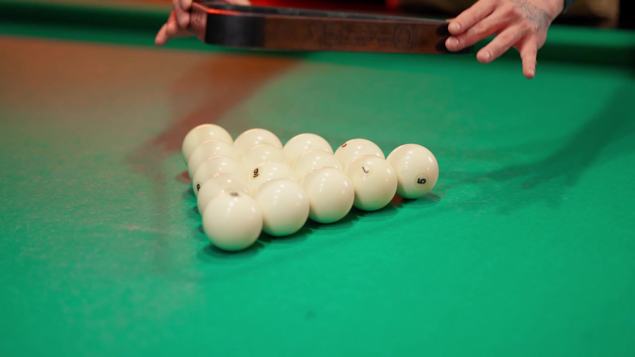 Mains rangeant des boules de billard blanches sur une table de billard verte