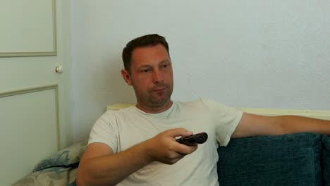 hombre aburrido de ver tv en casa