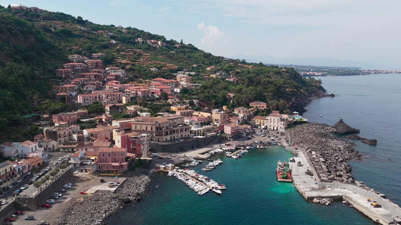 Vista aerea all'ora d'oro su Santa Maria la Scala, un villaggio di pescatori con acqua blu e scogliere di lava basaltica vicino all'Etna ad Acireale, Catania, Sicilia, Italia, una destinazione popolare sulla costa ionica.