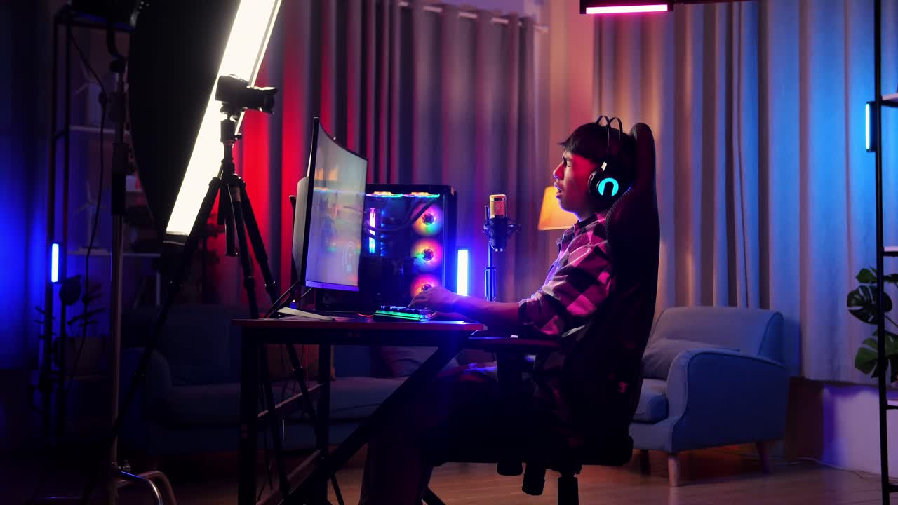 vista lateral de un niño asiático que juega a un juego en red en una computadora personal. bostezando y durmiendo, videojuego de transmisión en vivo, escritorio iluminado por luz de tira led rgb