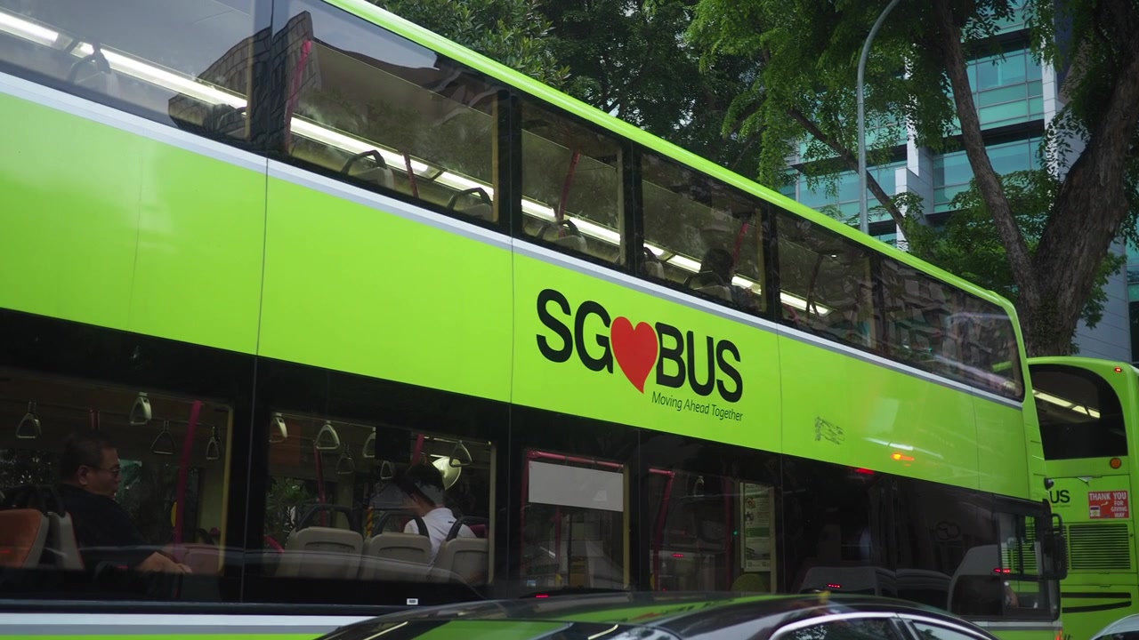 Bus tingkat hijau melaju melewati jalanan kota Singapura