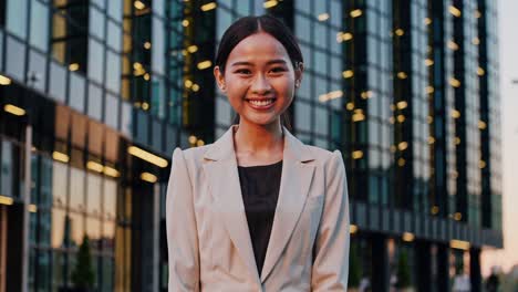 confident young businesswoman smiling in front of modern office building, showcasing her professionalism and success in the corporate world