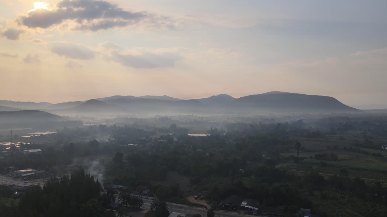 Aerial Drone Footage with Morning Sunrise of the Landscape of Thailand with Low Laying Mist on the Surrounding Mountainous Range.